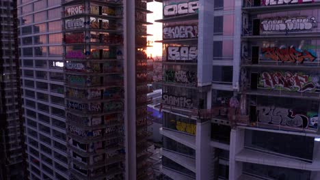 Close-up-descending-aerial-shot-of-the-unfinished-Oceanwide-Plaza-graffiti-buildings-in-downtown-Los-Angeles,-California-at-sunset