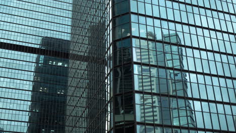 Moderne-Wände-Bestehen-Aus-Glas-Und-Stahl-Mit-Reflexionen-Von-Gebäuden-Und-Blauem-Himmel
