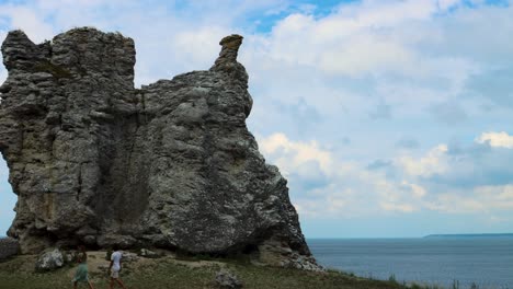 Young-couple-walk-by-rauk-cliff-by-ocean,-cloudy-day,-Gotland,-Sweden