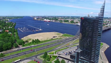 Modern-skyscraper-of-Riga-with-famous-bridge-behind,-aerial-drone-view