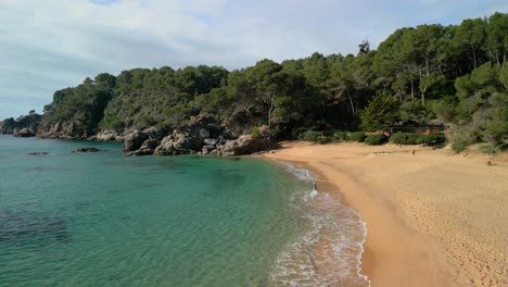 Capture-the-essence-of-Lloret-De-Mar's-coastal-charm-from-above,-highlighting-the-crystal-clear-waters-and-exclusive-getaways-of-Santa-Cristina-and-Cala-Treumal