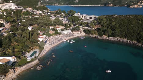 High-angle-bird's-eye-view-above-coastal-bay-of-Corfu-Greece-with-rows-of-beach-umbrellas-from-hotel