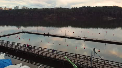 Aerial-pan-of-people-exercising-on-bridge-by-still-river-in-Sweden