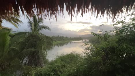 A-tranquil-lake-surrounded-by-lush-greenery,-palm-trees,-and-misty-hills