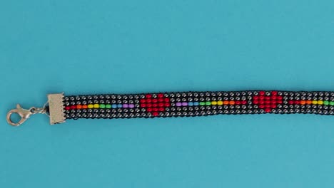 Handmade-LGBT-bead-pattern-necklace-over-turquoise-background