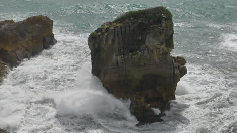 Slow-motion-wave-crashes-on-sea-stack-on-coast---Punakaiki,-New-Zealand