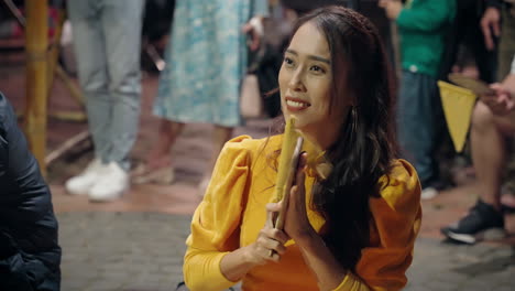 Vietnamese-woman-in-yellow-outfit-clapping-hands-with-flag-and-paddle-playing-traditional-game-in-Hoi-An