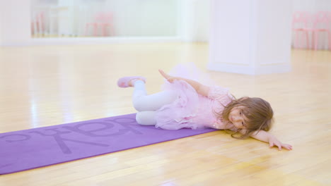 Entzückende-Kleine-Ballerina-In-Einem-Rosa-Tutu-Kleid-Streckt-Sich-Und-übt-Ballettübungen-Im-Studio-Auf-Dem-Boden-Liegend