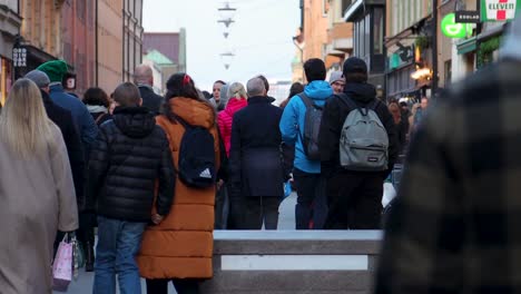 Close-rear-view-of-people-walking-on-street-in-Stockholm,-slomo