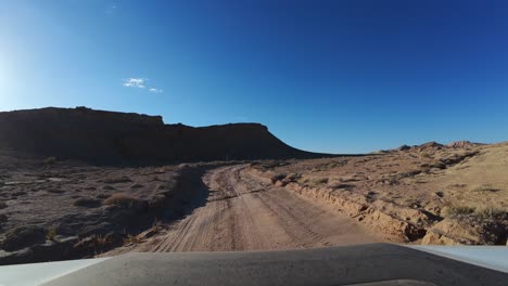 FPV-driving-on-empty-desert-dirt-road-on-sunny-day,-Bentonite-Hills,-Utah