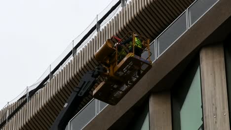 Builders-on-a-crane-ensuring-the-new-Google-HQ-is-built-correctly,-London,-United-Kingdom