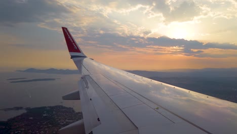 Wing-of-airplane-descending-over-French-riviera-coast-at-cloudy-sunset