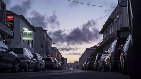 Traveling-cars-pass-by-parked-in-a-street-with-hotels-and-shops---Evening-to-Night-Time-Lapse