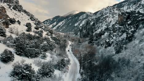 Toma-Aérea-De-Seguimiento-De-Vehículos-Conduciendo-A-Través-De-Un-Cañón-Nevado-En-Utah.