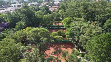 Movimiento-Hacia-Adelante-Con-Drones-Filmando-Hermosas-Canchas-De-Tenis-En-Medio-De-árboles-Y-Mucha-Naturaleza,-Temprano-En-La-Mañana