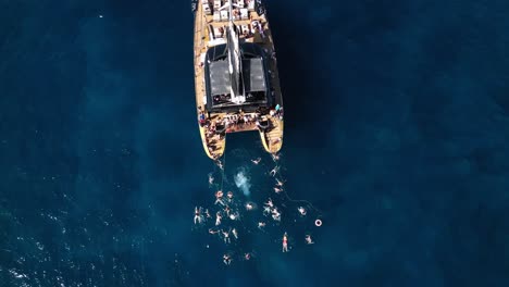 Mann-Springt-Vom-Boot-Ins-Wasser,-Katamaran-Im-Blauen-Meerwasser,-Wunderschöne-Bucht-Auf-Einer-Insel,-Teneriffa,-Boot,-Sommer,-Drohne