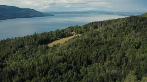 Sunny-aerial-view-of-house-next-to-the-lake-between-Norway-mountains
