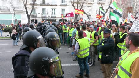 Polizisten-Stehen-Wache-Vor-Spanischen-Landwirten-Und-Agrargewerkschaften,-Die-Sich-Auf-Der-Plaza-De-La-Independencia-Versammeln,-Um-Gegen-Unlauteren-Wettbewerb,-Agrar--Und-Regierungspolitik-Zu-Protestieren
