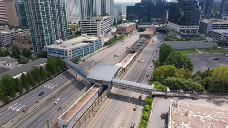Aerial-birds-eye-shot-of-pedestrian-bridge-over-highway-with-traffic-in-sun