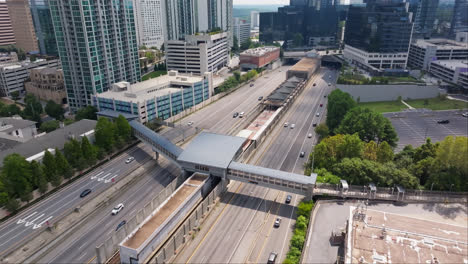 Toma-Aérea-De-Un-Puente-Peatonal-Sobre-Una-Autopista-Con-Tráfico-Bajo-El-Sol