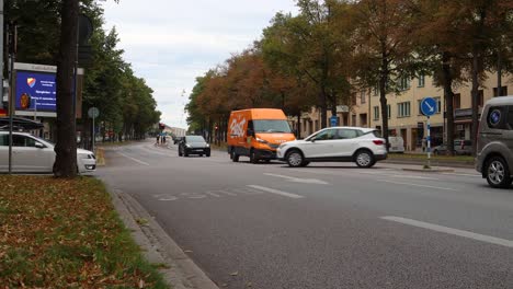 Car-traffic-on-street-in-Stockholm-lined-by-trees-in-autumn,-static