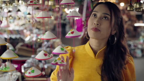 Mujer-Bonita-Asiática-Tocando-Souvenirs-Vietnamitas-En-El-Mercado-Nocturno-De-Hoi-An.