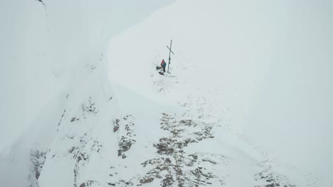 Los-Esquiadores-Alpinos-Están-Parados-En-La-Cima-De-La-Montaña-Cubierta-De-Nieve-Cerca-De-La-Cruz.