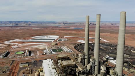 Eine-Drohnenaufnahme-Des-„Navajo-Generating-Station“,-Einem-Riesigen-Kohlekraftwerk-Und-Industriekomplex-Mit-Hohen-Schornsteinen,-Mitten-In-Der-Wüste-Der-Navajo-Nation,-In-Der-Nähe-Von-Page,-Arizona