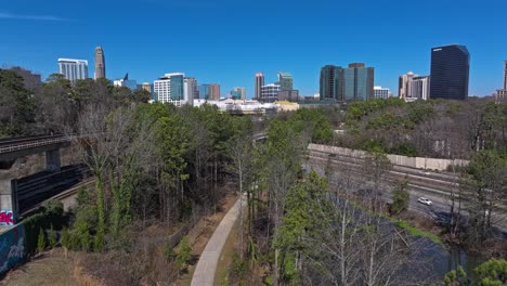 Rail-Tracks,-park-path-and-busy-highway-in-front-of-modern-skyline-in-Atlanta-City,-USA