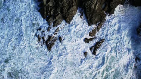 White-Water-Swirling-Around-Cornish-Slate-Rocks-with-a-Top-Down-Aerial-Shot-in-Slow-Motion