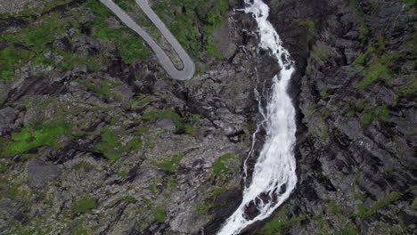 Toma-Aérea-De-Arriba-Hacia-Abajo-De-La-Cascada-Trollfossen-Cayendo-Por-Un-Acantilado-Hacia-El-Río-TVerelva-En-Noruega