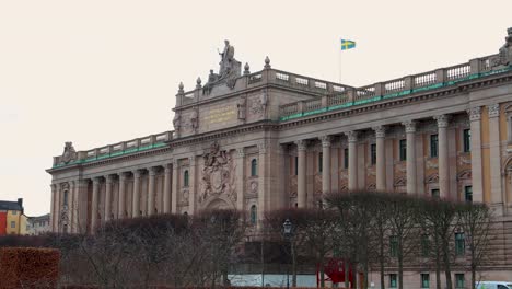 Swedish-parliament-building-with-flag-on-top-on-cloudy-day,-Stockholm