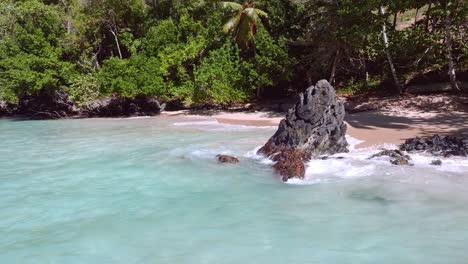 Rocky-stones,-boulders-on-tropical-sand-beach,-turquoise-waves-breaking