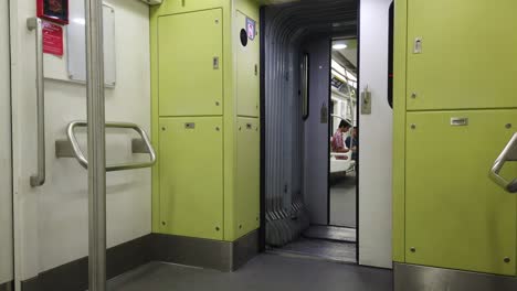 An-empty-train-wagon-with-a-lonely-person-looking-at-the-phone-in-subway-metro-underground-green-railway,-panoramic-cinematic-wide-view