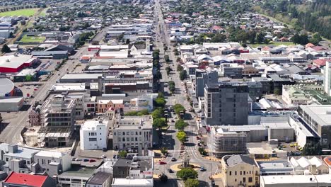 Invercargill-iconic-roundabout-with-statue-and-traffic-on-main-street,-drone-reveal-cityscape