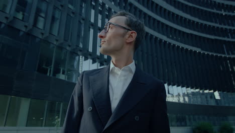 Handsome-Caucasian-Man-In-Suit-Standing-Outdoors-At-Financial-District-Looking-Around-At-Buildings