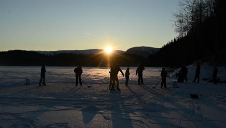 Freunde-Spielen-Eishockey-Auf-Dem-See-Bei-Wunderschönem,-Lebhaftem-Sonnenuntergang,-Norwegische-Zeitlupe