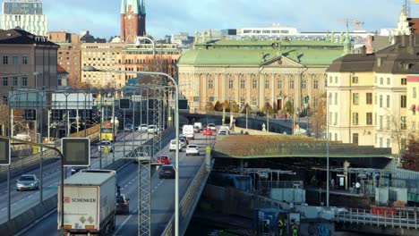 Cars-and-trucks-drive-on-bridge-in-central-Stockholm,-evening-sunlight