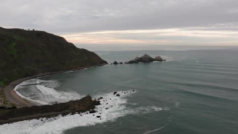 Drone-panning-shot-to-the-right-of-a-beach-alcove-in-pacifica,-california