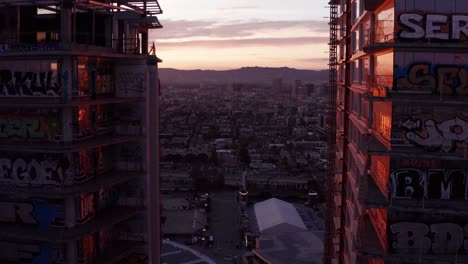 Nahaufnahme-Einer-Umgekehrten-Pullback-Luftaufnahme-Der-Einzigartigen-Graffiti-Wandmalereien-Auf-Den-Balkonfenstern-Der-Verlassenen-Wolkenkratzer-Der-Oceanwide-Plaza-In-Der-Innenstadt-Von-Los-Angeles,-Kalifornien-Bei-Sonnenuntergang