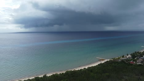 Cozumel-beach-with-approaching-storm-clouds-over-turquoise-sea,-daylight,-aerial-view