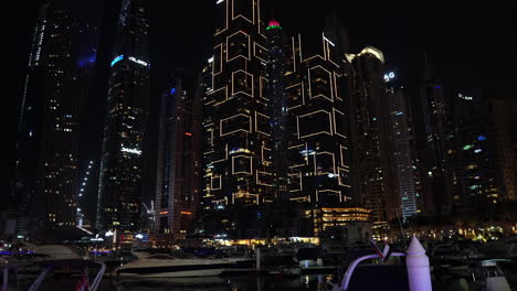 Dubai-Marina-Emiratos-Árabes-Unidos-Por-La-Noche,-Yates-Amarrados-Y-Barcos-Bajo-Rascacielos-En-Luces