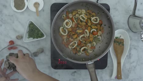 Chef's-hands-putting-seafood-ingredients-into-pan_top-view