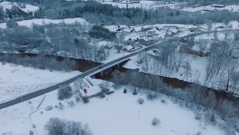 Snow-covered-landscape-of-Abava-river-Renda-village-,-aerial-view,-serene-winter-day,-moving-forward,-tilt-down