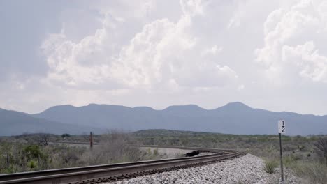 Train-tracks-in-foreground-and-endless-Texas-skies-surrounding,-with-mountains-in-the-background