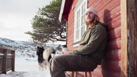 The-Man-is-Savoring-a-Hot-Beverage-with-His-Dog-During-Winter-in-Bessaker,-Trondelag-County,-Norway---Close-Up