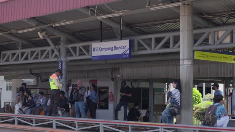 Passengers-waiting-at-Bo-Kampung-Bandan-train-station-platform-in-Tangerang-Selatan,-Indonesia,-daylight