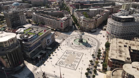 Aerial-View-of-Square-Macedonia,-Skopje,-Downtown-Buildings,-Alexander-The-Great-Monument-and-People-on-Sunny-Day---Establishing-Drone-Shot