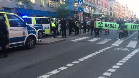 Schwenk-Vom-Polizeiauto-Auf-Demonstranten-Mit-Banner-Bei-Demonstration,-Schweden