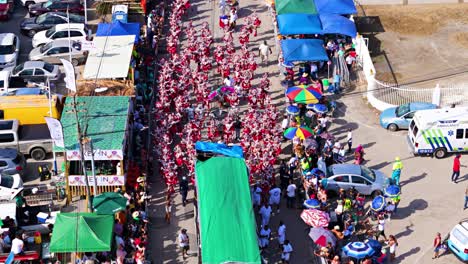 Eine-Drohne-Fliegt-über-Karnevalskünstler,-Die-Auf-Der-Tropischen-Insel-Curaçao-Die-Straße-Entlang-Marschieren